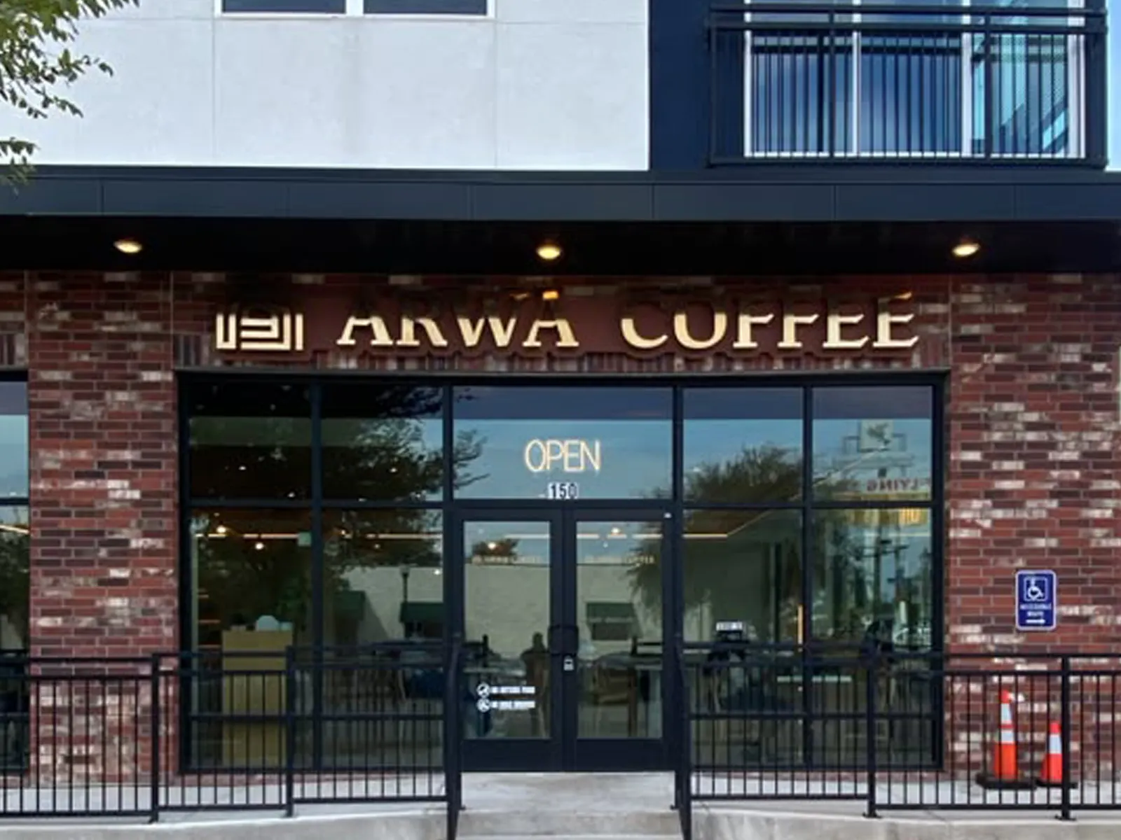 Arwa Coffee dimensional letters above the glass entrance of a brick mixed-use building