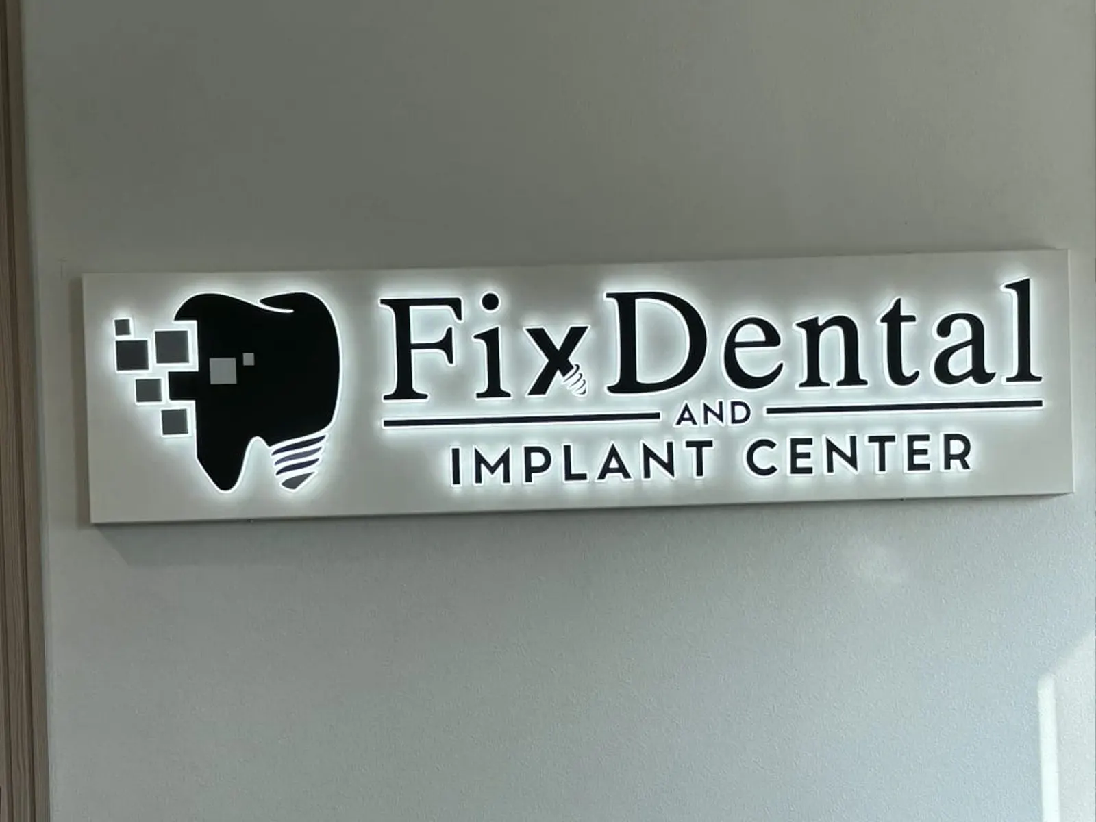 Fix Dental and Implant Center backlit logo panel glowing on an interior wall