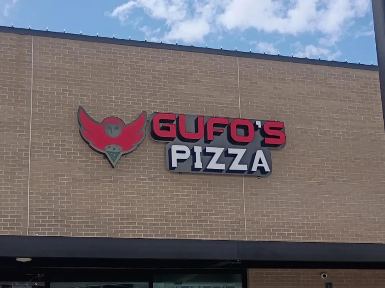 Gufo's Pizza red and white channel letters with an owl logo on a tan brick wall