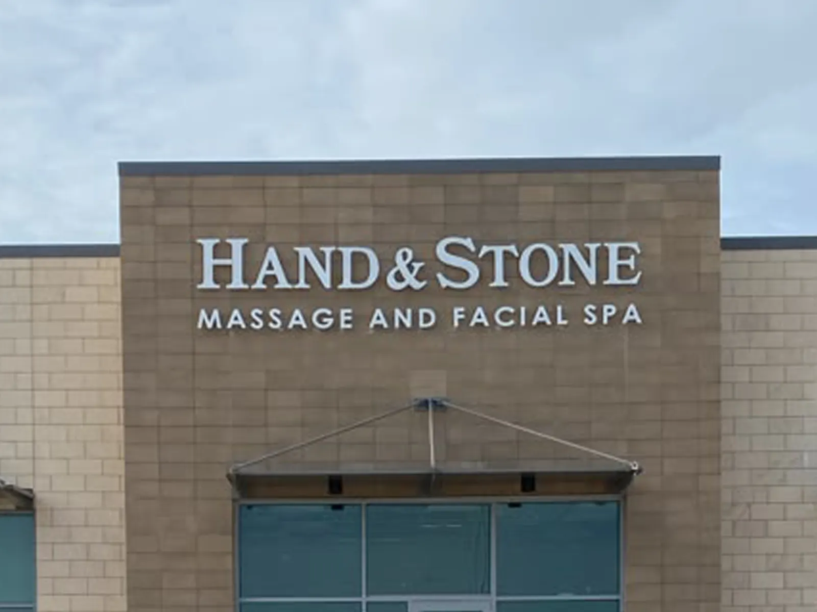 Hand and Stone Massage and Facial Spa dimensional letters on a tan masonry facade