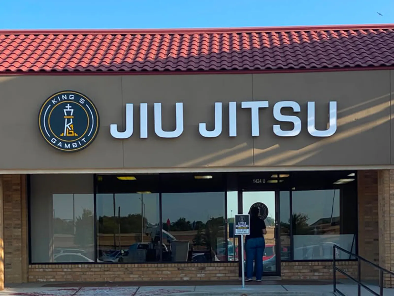 King's Gambit Jiu Jitsu circular logo and white letters on a dark fascia under a tile roof