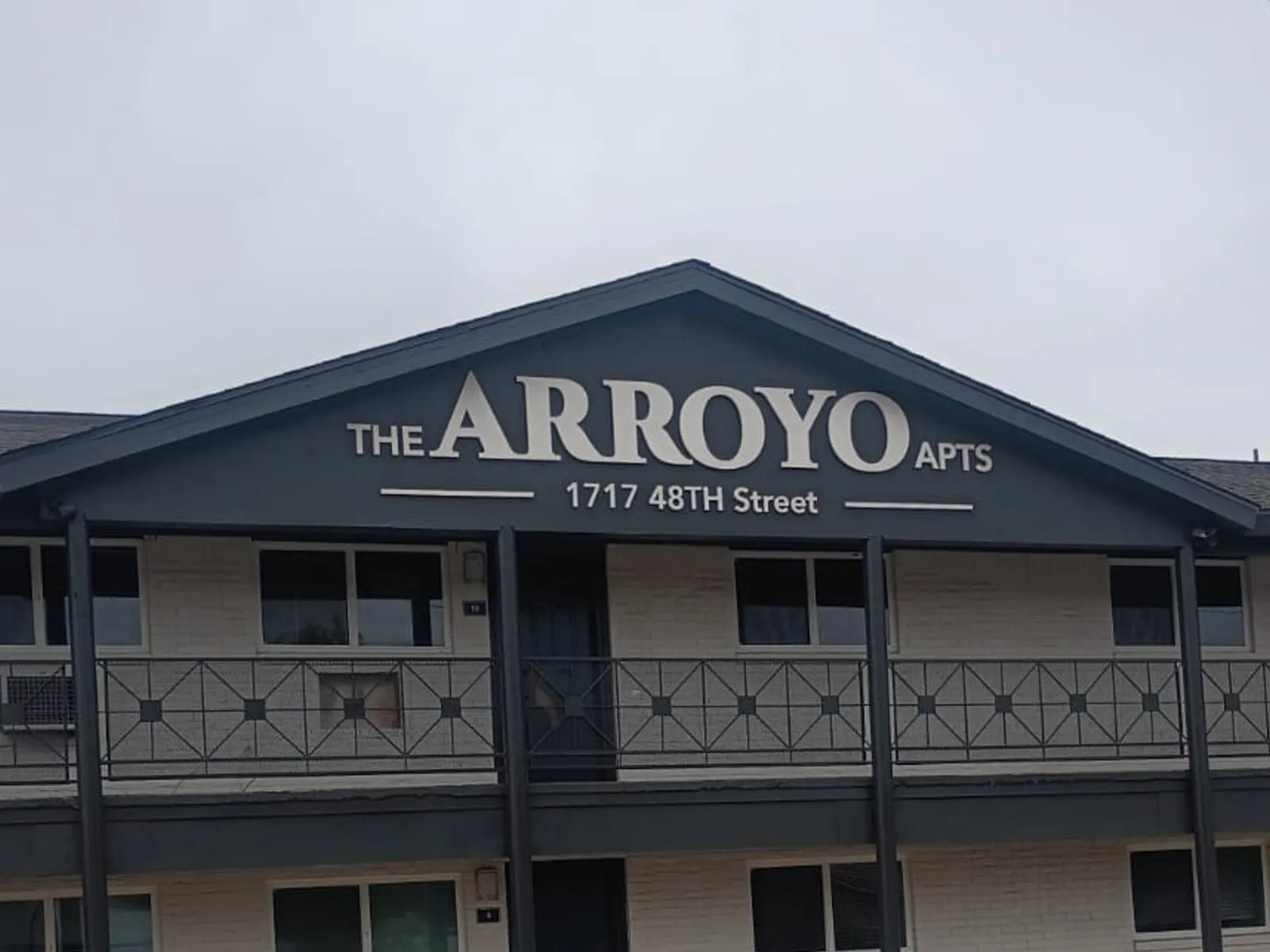 The Arroyo Apts dimensional letters and street address on the gable of an apartment building